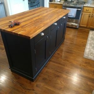 black kitchen island with wood top and drill on top